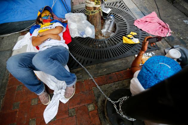 Anti-government protesters lie chained at a protest as they camp in front of UN offices in Caracas