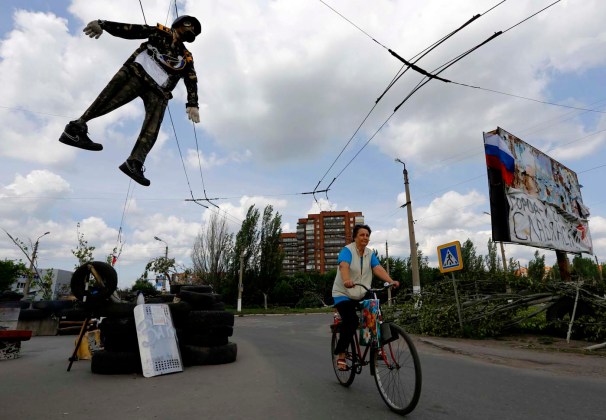 Una efigie de un soldado ucraniano cuelga por encima de un punto de control de pro-ruso como ciclos mujer locales a través de la entrada de la ciudad ucraniana oriental de Slaviansk / Yannis Behrakis / Reuters