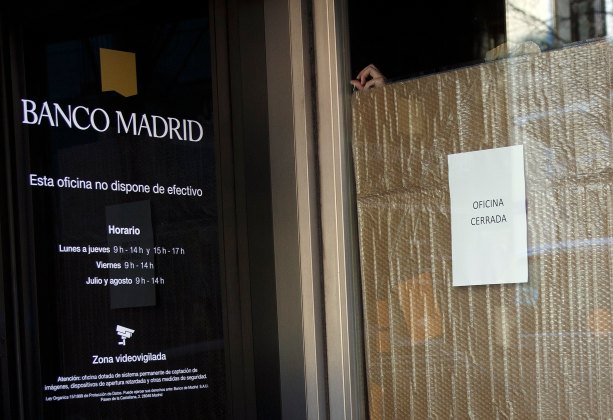 Employee covers the door of a Banco Madrid branch in Madrid