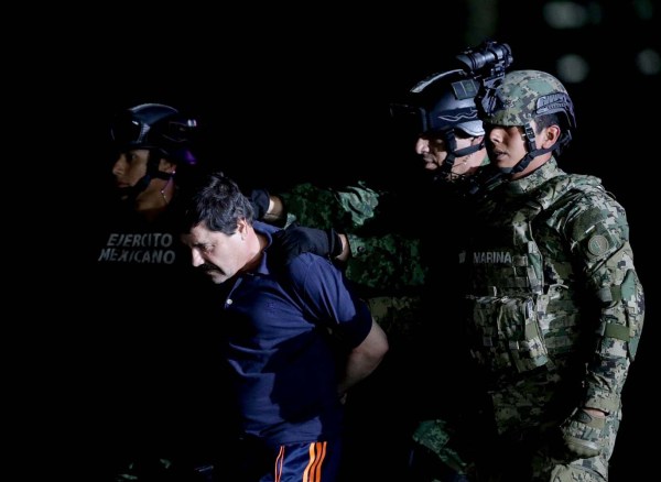 Recaptured drug lord Joaquin "El Chapo" Guzman is escorted by soldiers at the hangar belonging to the office of the Attorney General in Mexico City, Mexico January 8, 2016.  REUTERS/Henry Romero