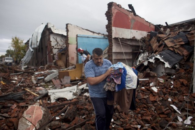 Residents salvage possessions from the remains of their house hit by a tornado in Dolores, Uruguay on April 16, 2016. At least four people were killed and seven severely injured Friday by a tornado 265 km west of Montevideo, official sources reported. / AFP PHOTO / Nicolas Garcia