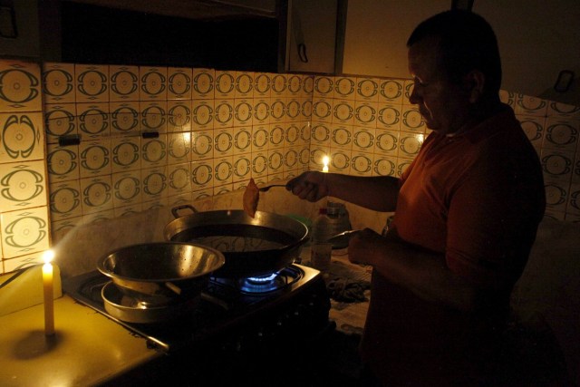 Un hombre cocina a la luz de las velas en San Cristóbal. Foto: REUTERS/Carlos Eduardo Ramirez