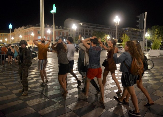 Un grupo de personas cruza la calle con sus manos en las cabezas mientras soldados franceses aseguran el área después de que al menos 75 personas murieron en Niza cuando un camión arrolló a una multitud que celebraba la fiesta nacional del Día de la Bastilla, 14 de julio de 2016.  REUTERS/Jean-Pierre Amet