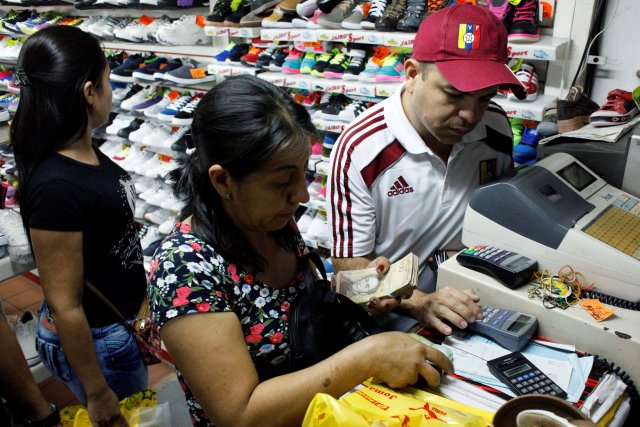 People pay using 100 bolivar notes at a shoe shop in San Cristobal, Venezuela, December 12, 2016. REUTERS/Carlos Eduardo Ramirez