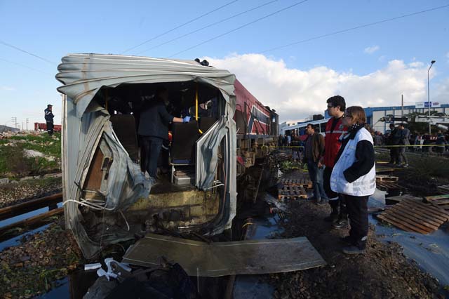 Tunisian security officers gather at the site of a collision, after a train slammed into a public bus and tore it in two , in the area of Jebel Jalloud, near Sidi Fathallah, about 10 kilometres (six miles) south of the Tunisian capital on December 28, 2016. At least five people were killed and more than 30 injured when a train slammed into a public bus near Tunis, the Tunisian interior ministry said. / AFP PHOTO / FETHI BELAID