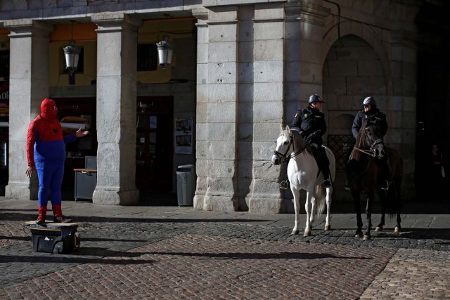 Police officers on horseback stand beside a street performer at Plaza Mayor square in Madrid, Spain January 16, 2017. REUTERS/Juan Medina