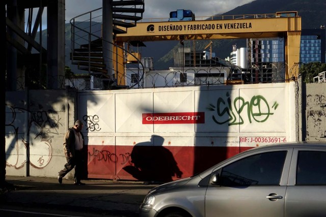 A man walks past corporate logo of Odebrecht in a construction site with a text in a structure that reads "Designed and made in venezuela" in Caracas
