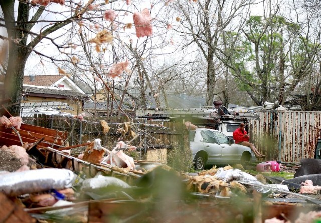 NEW ORLEANS, LA - FEBRUARY 07: A woman sits on a car surrounded by debris along Chef Menture Ave after a tornado touched down in the eastern part of the city on February 7, 2017 in New Orleans, Louisiana. According to the weather service, 25 people were injured in the aftermath of the tornado. Sean Gardner/Getty Images/AFP