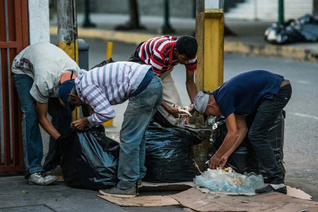 Personas buscan en la basura algopara comer ante la crisis actual en Venezuela.  / AFP PHOTO / Federico PARRA