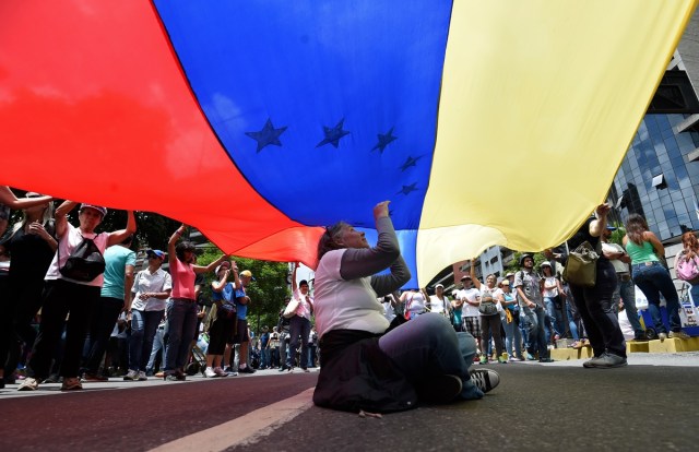 Venezuelan opposition activists demonstrate against President Nicolas Maduro in Caracas, on July 9, 2017. Venezuela hit its 100th day of anti-government protests on Sunday, one day after its most prominent political prisoner, Leopoldo Lopez, vowed to continue his fight for freedom after being released from jail and placed under house arrest. At least 91 people have died since non-stop street protests began on April 1. / AFP PHOTO / Juan BARRETO