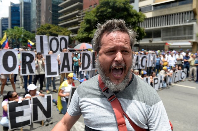 An opposition activist shouts slogans during a demonstration against Venezuelan President Nicolas Maduro in Caracas, on July 9, 2017. Venezuela hit its 100th day of anti-government protests on Sunday, one day after its most prominent political prisoner, Leopoldo Lopez, vowed to continue his fight for freedom after being released from jail and placed under house arrest. At least 91 people have died since non-stop street protests began on April 1. / AFP PHOTO / Federico PARRA