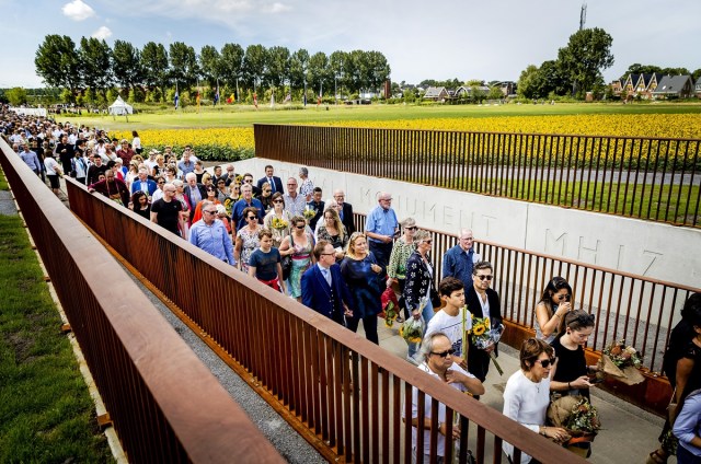 Relatives attend the unveiling of the National Monument for the MH17 victims in Vijfhuizen, on July 17, 2017. Three years after Flight MH17 was shot down by a missile over war-torn Ukraine, more than 2,000 relatives gather to unveil a "living memorial" to their loved ones. A total of 298 trees have been planted in the shape of a green ribbon, one for each of the victims who died on board the Malaysia Airlines flight en route from Amsterdam to Kuala Lumpur. The flowers also represent "the sunflower fields in eastern Ukraine where some parts of the plane wreckage were found". / AFP PHOTO / ANP / Remko de Waal / Netherlands OUT