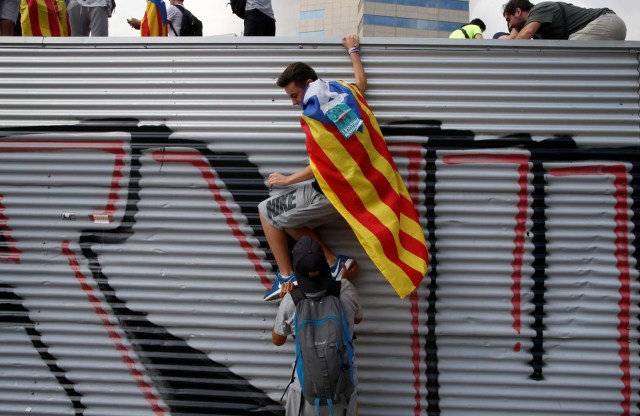 A student, wearing an Estelada (Catalan separatist flag), is helped to climb a wall during a demonstration in favour of the banned October 1 independence referendum in Barcelona, Spain September 28, 2017.  REUTERS/Jon Nazca