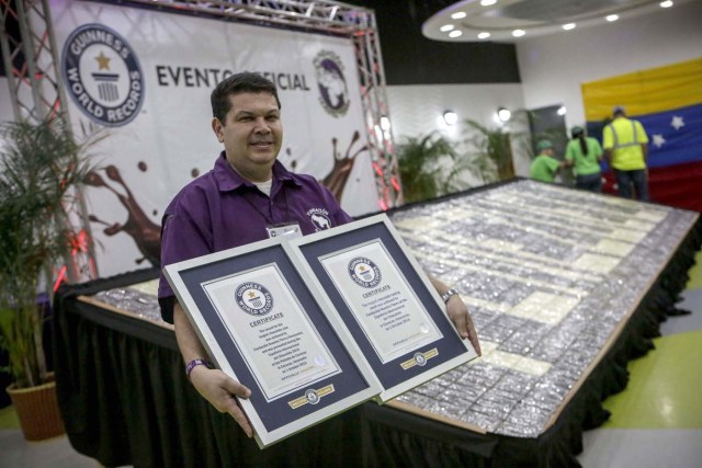 ACOMPAÑA CRÓNICA: VENEZUELA GASTRONOMÍA. CAR13. CARACAS (VENEZUELA), 29/09/2017.- Fotografía fechada el 28 de septiembre de 2017 que muestra a Naudys González, director de Proyectos de la Fundación Nuestra Tierra y organizador de la V Expoferia Internacional, mientras sostiene dos certificados de récord Guiness obtenidos en 2015 y 2016 por la moneda de chocolate más grande del mundo, de 874 kilogramos, y la cata más grande jamás vista, con al menos 600 participantes, en Caracas (Venezuela). La industria del chocolate en Venezuela organiza su V Expoferia Internacional para "darle impulso" exportador a sus productos, en medio de la rampante crisis económica que atraviesa el país petrolero, y con la mira puesta en otro récord Guinness que promocione el llamado "mejor cacao del mundo". EFE/Cristian Hernández