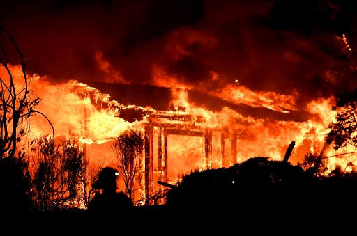 Firefighters assess the scene as a house burns in the Napa wine region of California on October 9, 2017, as multiple wind-driven fires continue to ravage the area burning structures and causing widespread evacuations.  / AFP PHOTO / JOSH EDELSON