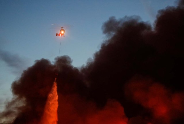 A helicopter dumps water on a fire at a construction goods market on the northwestern edge of Moscow, Russia October 8, 2017. REUTERS/Maxim Shemetov