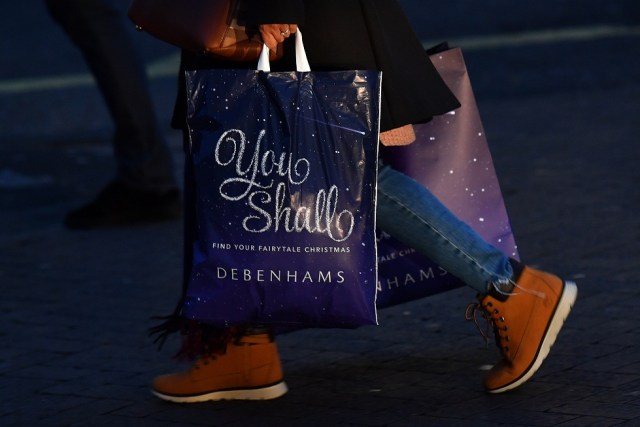 A shopper carries a Christmas-themed bag from the retailer Debenhams as they walk along Oxford Street in London, on November 23, 2017. Black Friday is a sales offer originating from the US where retailers slash prices on the day after the Thanksgiving holiday. In the UK it is used as a marketing device to entice Christmas shoppers with the discounts at stores often lasting for a week. / AFP PHOTO / Ben STANSALL