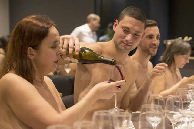 EDITORS NOTE: Graphic content / A nude diner fills wine for another at the newly opened nudist restaurant "o'naturel" in Paris on December 5, 2017. Leave your coats, your pants and your inhibitions at the door: a Paris restaurant has begun serving up classic French fare to diners in the nude. Located down a quiet side street in southwest Paris, O'naturel, billed as the French capital's first nudist restaurant, is the brainchild of 42-year-old twins Mike and Stephane Saada.  / AFP PHOTO / GEOFFROY VAN DER HASSELT / RESTRICTED TO EDITORIAL USE - TO ILLUSTRATE THE EVENT AS SPECIFIED IN THE CAPTION