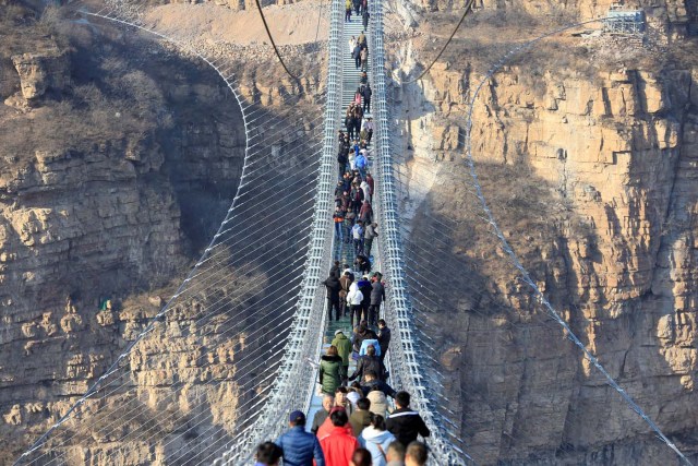 Visitors walk on the newly opened 488-metre-long glass suspension bridge at Hongyagu attraction in Pingshan, Hebei province, China December 26, 2017. Picture taken December 26, 2017. Zhang Haiqiang via REUTERS ATTENTION EDITORS - THIS IMAGE WAS PROVIDED BY A THIRD PARTY. CHINA OUT.
