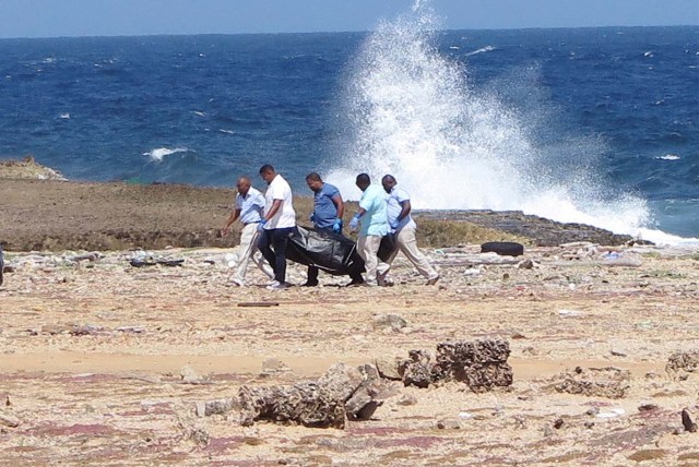 Forensic workers carry a bag containing the body of a person who was found at the shore, near Willemstad, Curacao January 10, 2018. Picture taken January 10, 2018. REUTERS/Umpi Welvaart