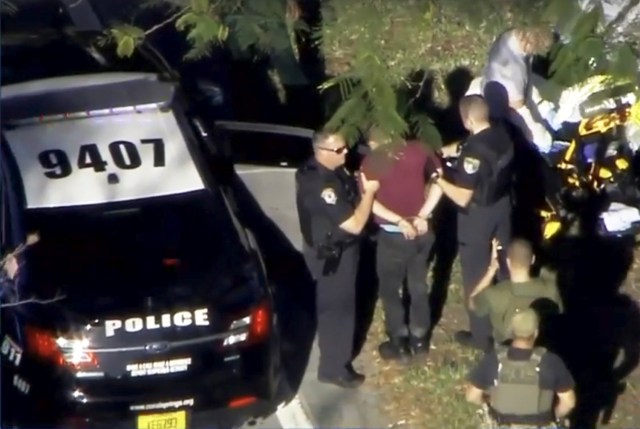 Un hombre esposado es conducido por la policía cerca de la escuela secundaria Marjory Stoneman Douglas luego de un tiroteo en Parkland, Florida, 14 de febrero de 2018 in a still image from video. WSVN.com via REUTERS