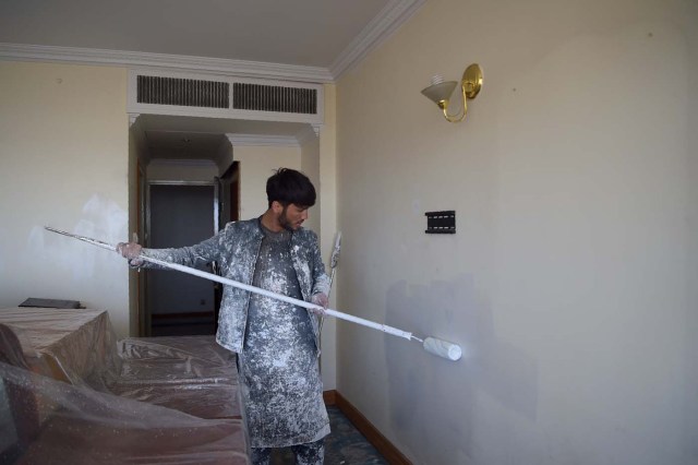 This photograph taken on March 7, 2018 shows an Afghan painter working inside a room of the Intercontinental Hotel in Kabul. Richard Clayderman's sweet-sounding "Romeo and Juliet" piano music accompanied Taliban gunmen as they rode in gold mirrored elevators to the upper floors of a Kabul luxury hotel in January in search of foreign guests to kill. At least 25 people, including 15 foreigners, were killed. Nearly seven weeks on, AFP was allowed to inspect the still badly damaged hilltop hotel overlooking the Afghan capital as it partially reopened its doors to the reluctant public. / AFP PHOTO / SHAH MARAI / TO GO WITH 'AFGHANISTAN-UNREST-HOTEL' SCENE by ALLISON JACKSON and EMAL HAIDARY