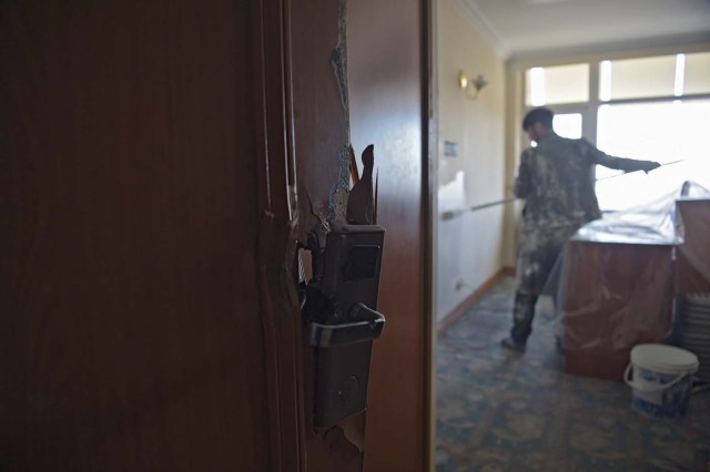 This photograph taken on March 7, 2018 shows an Afghan painter working inside a room with a damaged door at the Intercontinental Hotel in Kabul. Richard Clayderman's sweet-sounding "Romeo and Juliet" piano music accompanied Taliban gunmen as they rode in gold mirrored elevators to the upper floors of a Kabul luxury hotel in January in search of foreign guests to kill. At least 25 people, including 15 foreigners, were killed. Nearly seven weeks on, AFP was allowed to inspect the still badly damaged hilltop hotel overlooking the Afghan capital as it partially reopened its doors to the reluctant public.   / AFP PHOTO / SHAH MARAI / TO GO WITH 'AFGHANISTAN-UNREST-HOTEL'  SCENE by ALLISON JACKSON and EMAL HAIDARY