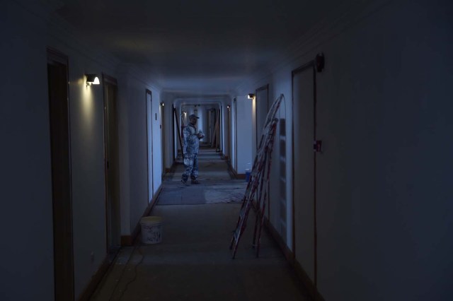 This photograph taken on March 7, 2018 shows an Afghan painter walking along a corridor of the Intercontinental Hotel in Kabul. Richard Clayderman's sweet-sounding "Romeo and Juliet" piano music accompanied Taliban gunmen as they rode in gold mirrored elevators to the upper floors of a Kabul luxury hotel in January in search of foreign guests to kill. At least 25 people, including 15 foreigners, were killed. Nearly seven weeks on, AFP was allowed to inspect the still badly damaged hilltop hotel overlooking the Afghan capital as it partially reopened its doors to the reluctant public. / AFP PHOTO / SHAH MARAI / TO GO WITH 'AFGHANISTAN-UNREST-HOTEL' SCENE by ALLISON JACKSON and EMAL HAIDARY