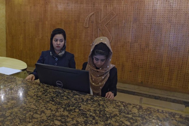 This photograph taken on March 7, 2018 shows receptionists working at the front desk of the Intercontinental Hotel in Kabul. Richard Clayderman's sweet-sounding "Romeo and Juliet" piano music accompanied Taliban gunmen as they rode in gold mirrored elevators to the upper floors of a Kabul luxury hotel in January in search of foreign guests to kill. At least 25 people, including 15 foreigners, were killed. Nearly seven weeks on, AFP was allowed to inspect the still badly damaged hilltop hotel overlooking the Afghan capital as it partially reopened its doors to the reluctant public. / AFP PHOTO / SHAH MARAI / TO GO WITH 'AFGHANISTAN-UNREST-HOTEL' SCENE by ALLISON JACKSON and EMAL HAIDARY