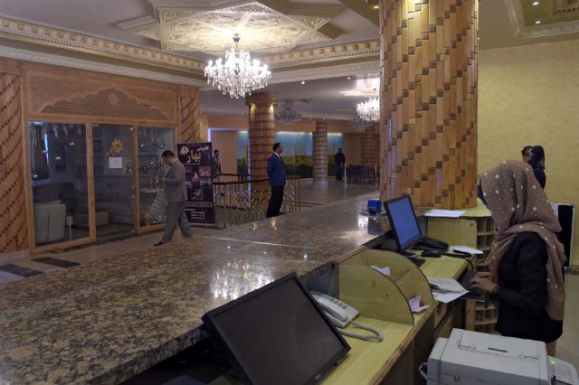 This photograph taken on March 7, 2018 shows receptionist working at the front counter of the Intercontinental Hotel in Kabul. Richard Clayderman's sweet-sounding "Romeo and Juliet" piano music accompanied Taliban gunmen as they rode in gold mirrored elevators to the upper floors of a Kabul luxury hotel in January in search of foreign guests to kill. At least 25 people, including 15 foreigners, were killed. Nearly seven weeks on, AFP was allowed to inspect the still badly damaged hilltop hotel overlooking the Afghan capital as it partially reopened its doors to the reluctant public. / AFP PHOTO / SHAH MARAI / TO GO WITH 'AFGHANISTAN-UNREST-HOTEL' SCENE by ALLISON JACKSON and EMAL HAIDARY