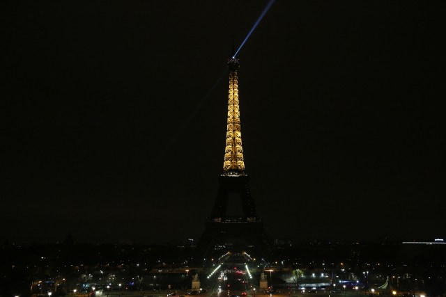 The lights of the Eiffel Tower are dimmed at midnight, March 23, 2018 in Paris to honor victims killed at a supermarket in southwest France by a man claiming allegiance to the Islamic State. Paris Mayor Anne Hidalgo announced that the Eiffel Tower would switch off its light at midnight to honour the victims. / AFP PHOTO / Zakaria ABDELKAFI