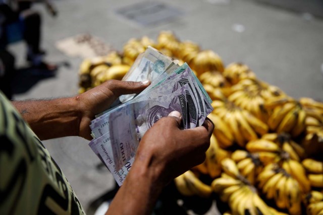 A street vendor counts bolivar notes as he waits for clients in Caracas, Venezuela March 23, 2018. REUTERS/Carlos Garcia Rawlins