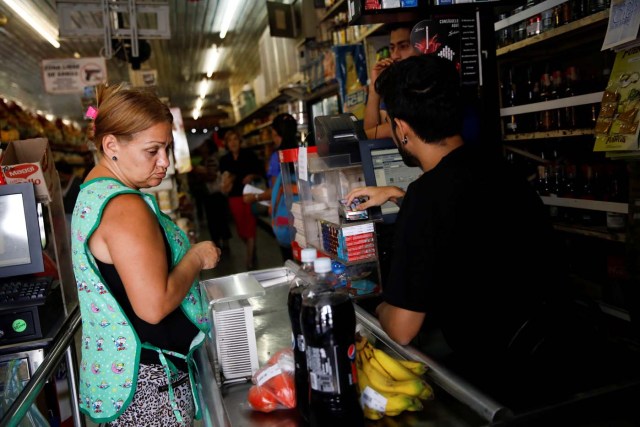 A woman pays for goods to the cashier at a supermarket in Caracas, Venezuela March 23, 2018. REUTERS/Carlos Garcia Rawlins