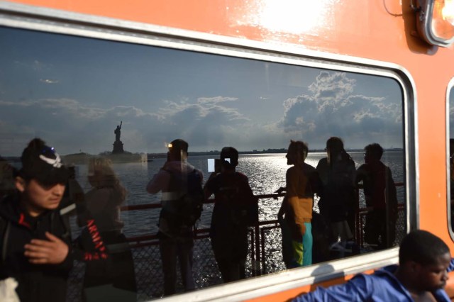 People ride the Staten Island Ferry while passing the Statue of Liberty, in New York City, on April 28, 2018. / AFP PHOTO / HECTOR RETAMAL