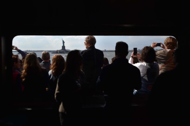 People take photos from the Staten Island Ferry while looking at the Statue of Liberty, in New York City, on April 28, 2018. / AFP PHOTO / HECTOR RETAMAL