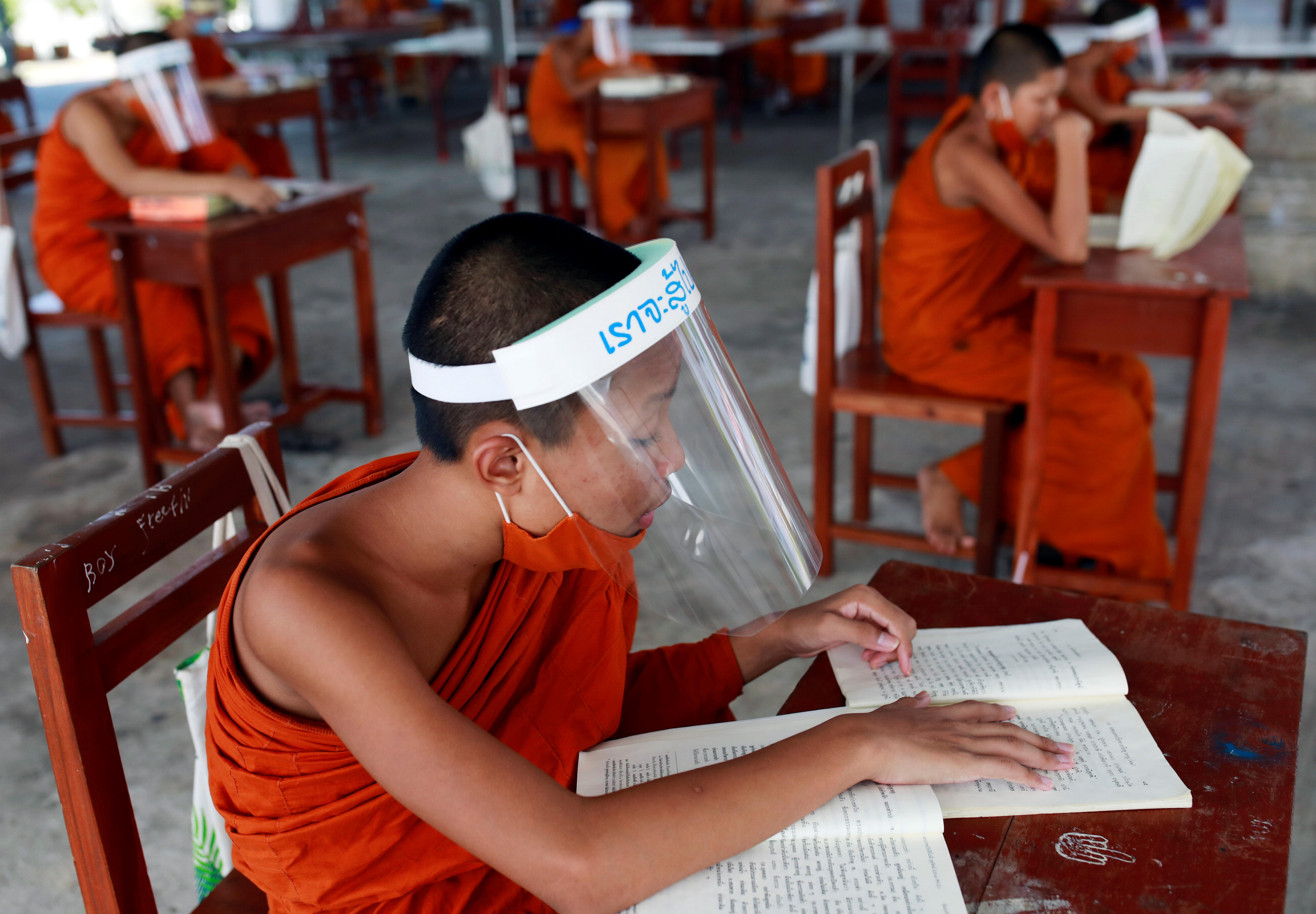 Monjes con mascarillas: Novicios budistas tailandeses estudian guardando la distancia social